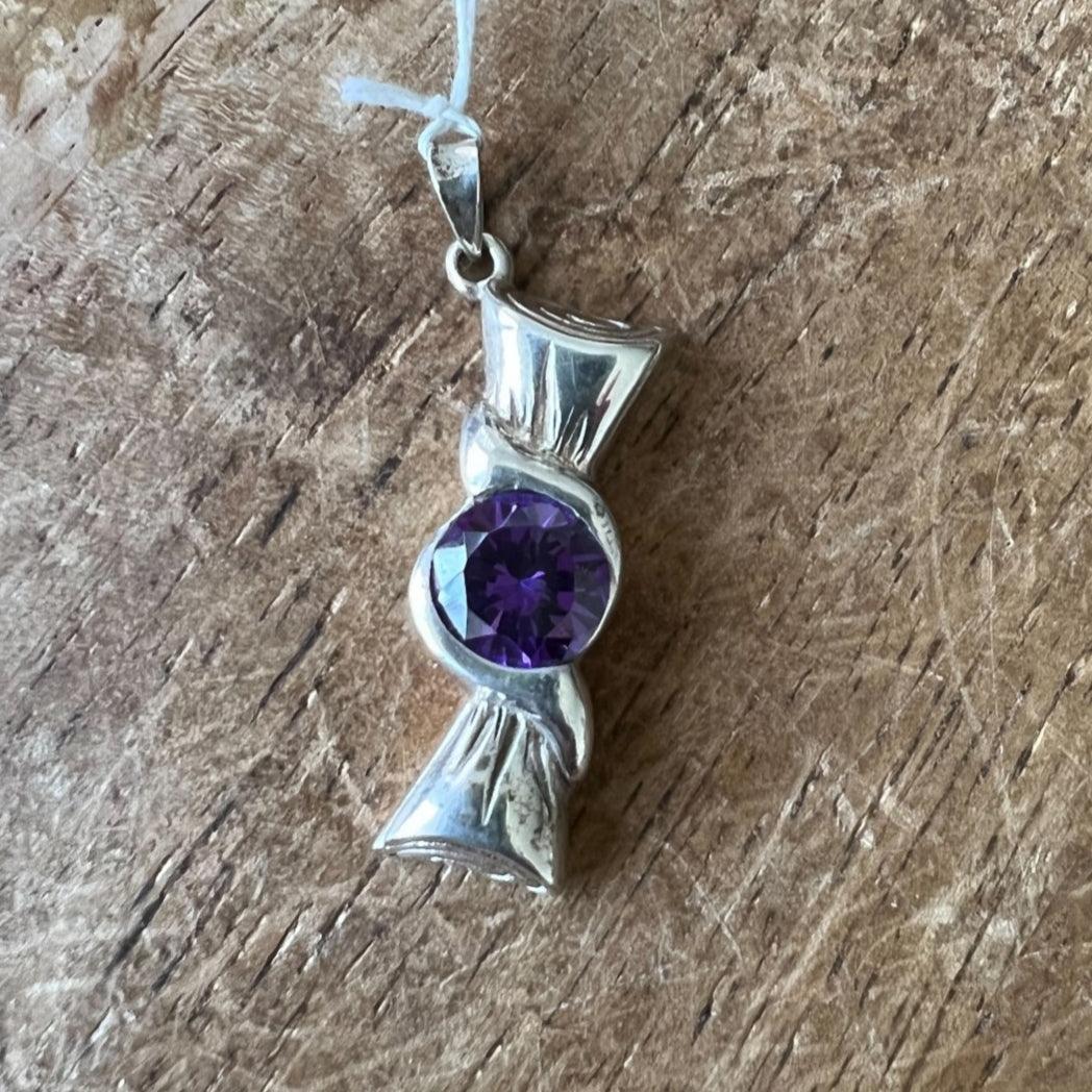 The round purple CZ in the Ribbon Pendant - Sterling Silver